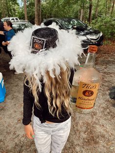 a woman wearing a feather hat next to a bottle