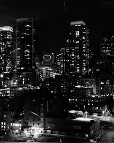 black and white photo of city at night with lights on buildings in the foreground