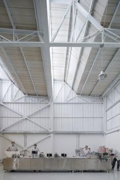 two men are working in a large industrial building with white walls and metal beams on the ceiling