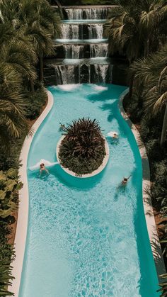 an aerial view of a pool with waterfall and people swimming in the water near it