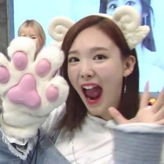 a woman with her hands up in the air while wearing a fake animal paw costume