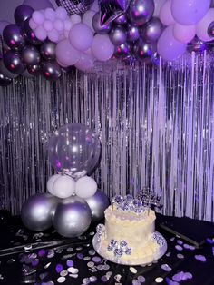 a birthday cake sitting on top of a table next to balloons and confetti