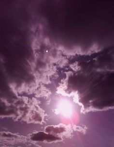 the sun shines brightly through clouds in this purple and blue sky with white fluffy clouds