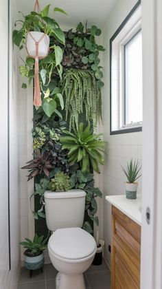 a white toilet sitting in a bathroom next to a green plant wall on the wall