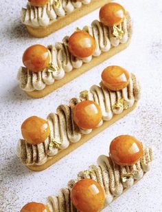 three desserts with orange and white toppings are arranged in rows on a table