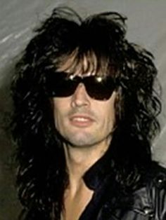 a man with long hair wearing sunglasses and a leather jacket is looking at the camera