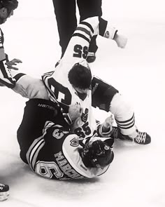 two hockey players collide on the ice as one falls to the ground and another lays down