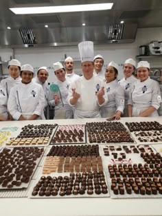 a group of chefs standing behind a table full of chocolates