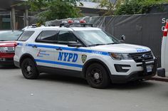 a nypd police car parked in front of a building with other cars behind it