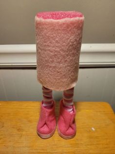a pair of pink slippers sitting on top of a wooden table next to a wall