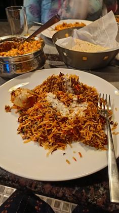 a white plate topped with lots of food next to bowls of rice and silverware