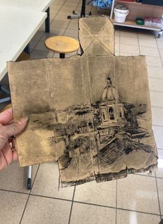 a person holding up a piece of paper with a drawing on it