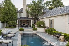 a house with a swimming pool in the front yard and patio furniture on either side