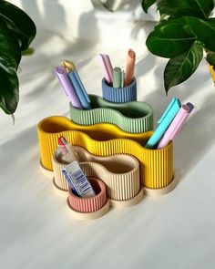 an assortment of colorful toothbrushes and other items on a white surface next to a potted plant
