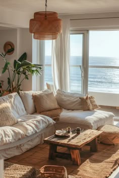 a living room filled with lots of furniture and a large window next to the ocean