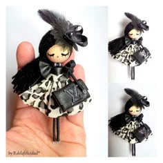 a hand holding a small doll with black hair and an animal print dress on it
