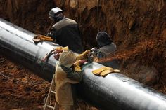 two men are working on a pipe in the middle of a construction site stock images