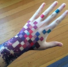a person's hand with colorful designs painted on the arm and wrist, in front of a wooden floor
