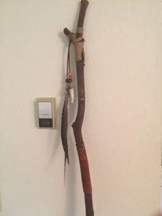 a wall mounted telephone next to a tree branch with an arrow hanging from it's side