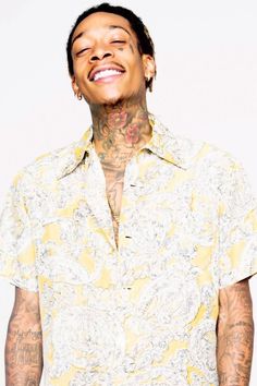 a man with tattoos and yellow shirt smiling