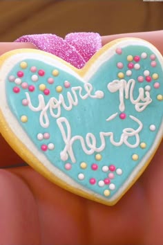 a cookie shaped like a heart with the words you're my hero written on it
