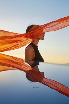 a woman with her hair blowing in the wind and wearing an orange scarf over her head