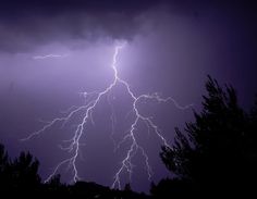 a lightning bolt is seen in the sky above some trees