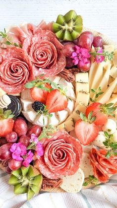 a platter filled with lots of different types of cheese and fruit on top of a table