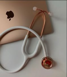 a white stethoscope sitting on top of an apple laptop next to it
