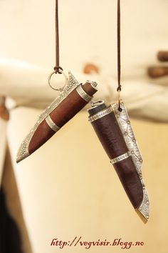 two knives hanging from strings in the shape of pendants with diamond accents on them