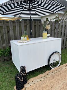 an outdoor ice cream cart with black and white striped umbrella over it's top