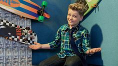 a young boy is sitting on the floor with his skateboard in front of him