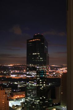 the city skyline is lit up at night with skyscrapers in the foreground and lights on