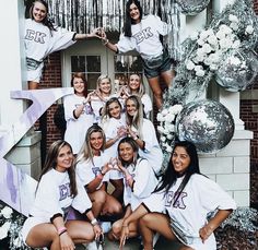 a group of women posing for a photo in front of a building with balloons and streamers