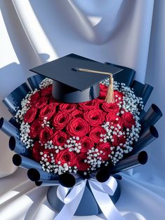 a bouquet of roses in the shape of a heart with a graduation cap on top