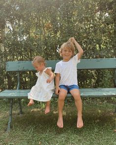 two young children sitting on a green bench