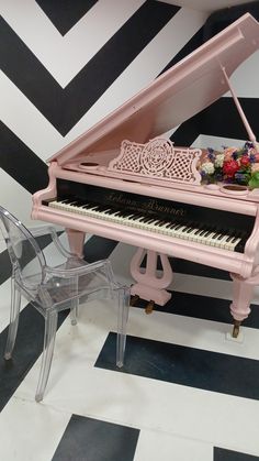 a pink piano sitting on top of a black and white floor next to a chair