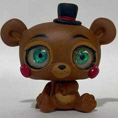 a brown teddy bear with green eyes and a top hat