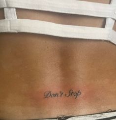 a woman's back with the words don't stop tattooed on her left side