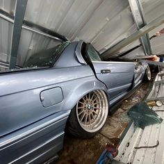 a blue car parked in a garage with it's hood up and the door open