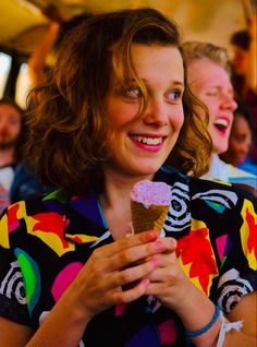 a woman eating an ice cream cone in front of a group of people on a bus