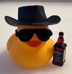 a rubber duck wearing sunglasses and a hat with a bottle of whiskey next to it