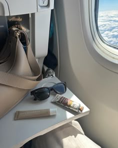 an airplane seat with sunglasses and a purse on it