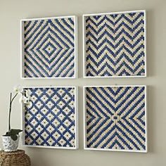 three blue and white wall art hanging on a wall next to a vase with flowers