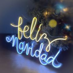 there is a neon sign that says feliz navidad next to a christmas tree