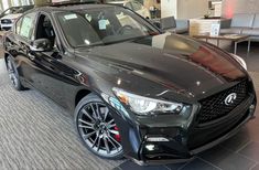 a black infiniti car is on display at a dealership with other cars