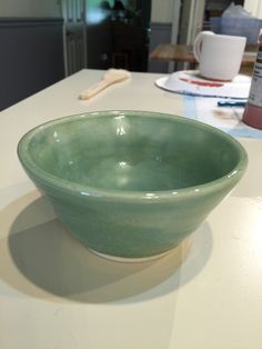 a green bowl sitting on top of a white counter