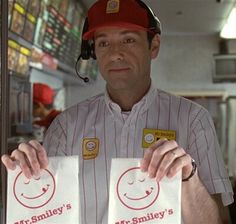 a man in a baseball uniform holding two bags with smiley faces on them and the caption mr smiley's art smiley's