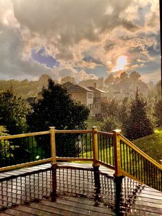 the sun is shining through the clouds over a deck with railings and trees in the foreground