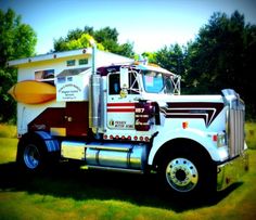 a large white truck parked on top of a lush green field